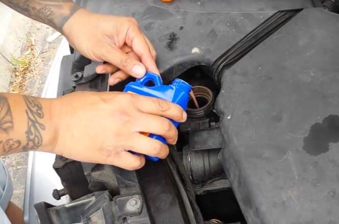 A customer carefully pours a small bottle of K-Seal in to fix his head gasket.